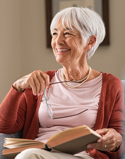Senior woman smiling while reading at home