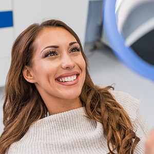 Woman smiling at reflection in handheld mirror