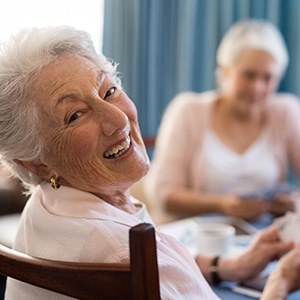 A woman with dentures playing cards with friends