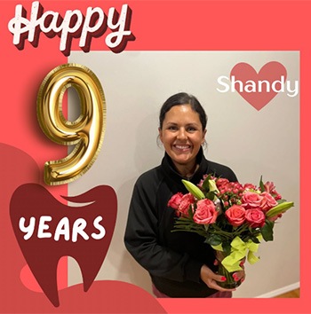 Smiling dental team member holding flowers with text saying happy 9 years Shandy