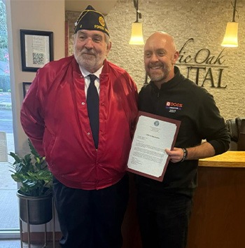 Doctor Jared holding a certificate with an older man in the dental office